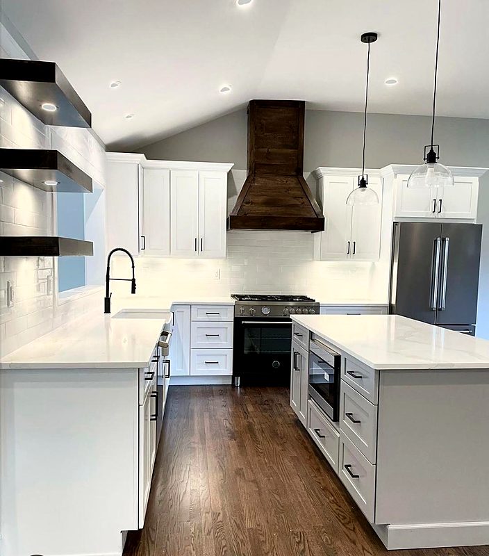 White shaker kitchen with a stained wood range hood, light gray island and floating shelves